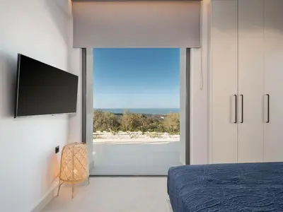 a bedroom with a large window with a view of the ocean at Villa Zefyros With Sea View in Plataniás