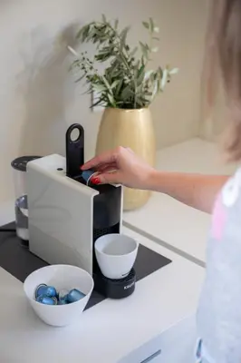 a woman is using a coffee maker on a counter at Seascape Kalyves in Kalyves