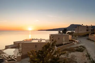 a sunset over a body of water with houses at Seascape Kalyves in Kalyves