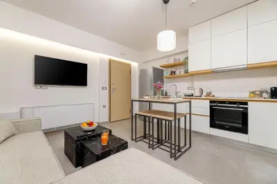 a kitchen with white cabinets and a tv on the wall at Penny's Apartment in Chania Town