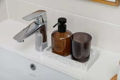 a bathroom sink with a bottle of soap and a cup at Penny's Apartment in Chania Town