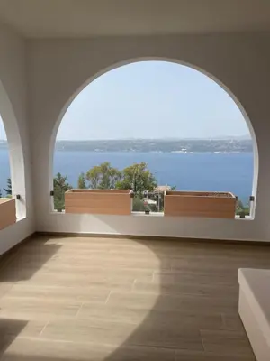 an empty room with a large window with a view of the ocean at Moments in Áptera