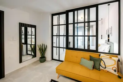 a yellow couch in a living room with windows at Boho Chic Retreat Suite in Chania Town
