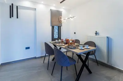 a dining room with a table and blue chairs at Seascape Luxury Apartment in Kounoupidhianá