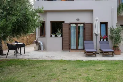 a patio with two chairs and a table in front of a house at Natalia's Apartment in Tavronitis in Tavronitis