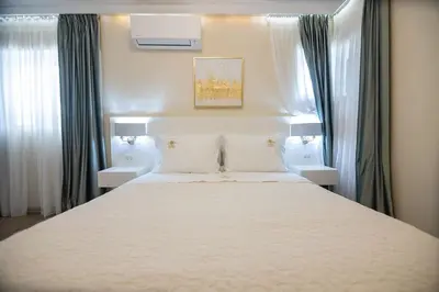 a bedroom with a large white bed with two windows at Nobel apartment, Chania Town in Chania Town