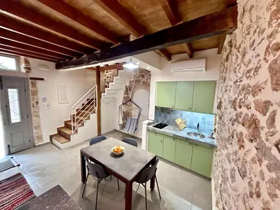 a kitchen with a table and a stone wall at Kazalakis Chania Harbor Roof top retreat in Chania Town