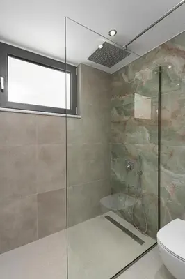 a bathroom with a glass shower and a toilet at LUXURY VILLA EOS Beachfront 20 metres from the sea in Nopíyia