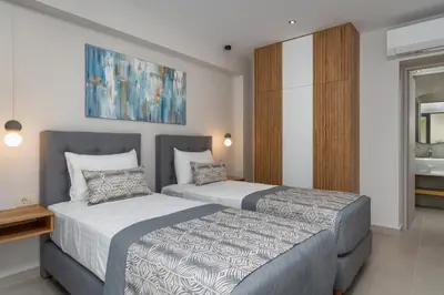 a bedroom with two beds and a painting on the wall at LUXURY VILLA EOS Beachfront 20 metres from the sea in Nopíyia