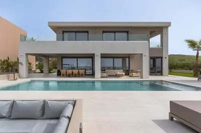 a villa with a swimming pool and a house at LUXURY VILLA EOS Beachfront 20 metres from the sea in Nopíyia