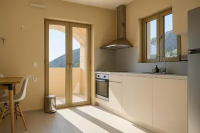 a kitchen with white cabinets and a glass door at Paliochora Beachfront Escape, Milolithos Pool Retreats in Palaiochóra