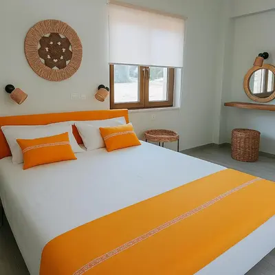 a bedroom with a large bed with orange and white pillows at Paliochora Beachfront Escape, Milolithos Pool Retreats in Palaiochóra