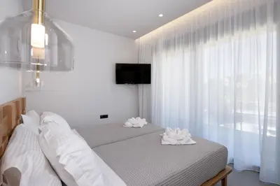 a bedroom with a bed with white sheets and a window at Punto De Vista Luxury Villas in Korakiaí