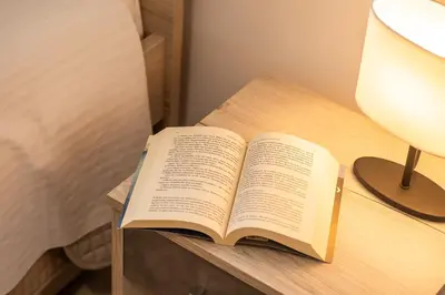 an open book on a table next to a lamp at Ampelos in Perivólia