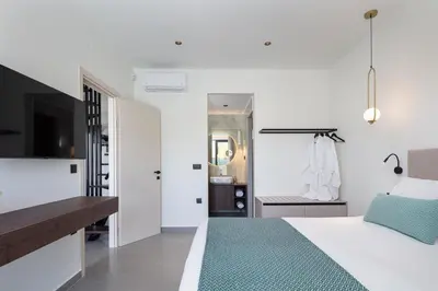 a white bedroom with a bed and a mirror at VillaSaints I Private Pool Villas, Walk to Beach, BBQ in Chania Town
