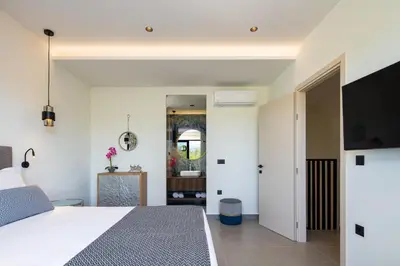 a bedroom with a bed and a flat screen tv at VillaSaints I Private Pool Villas, Walk to Beach, BBQ in Chania Town