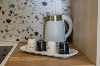 three coffee mugs on a plate next to a coffee pot at Central Bliss Apartment in Chania Town