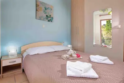 a bedroom with a bed with towels and a mirror at VALENA COZY MAISONETTE (15 min-ELAFONISI BEACH) in Élos