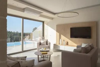 a living room with a couch and a tv and a table at Reflection Villa, Heated Pool & Absolute Seclusion, By ThinkVilla in Chania Town