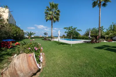 a garden with flowers in a barrel next to a pool at Socrates Holidays Apt. 1 with Pool near the Beach in Kamisianá