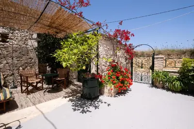 a garden with flowers in pots and a fence at The Fabrica Falasarna in Plátanos