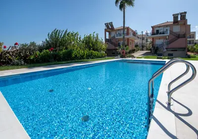 a swimming pool with blue water in front of a building at Socrates Holidays Apt. 2 with Pool near the Beach in Plataniás