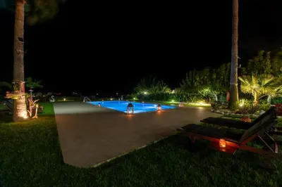 a swimming pool lit up at night with palm trees at Socrates Holidays Apt. 2 with Pool near the Beach in Plataniás