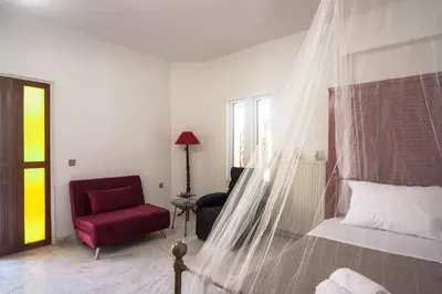 a bedroom with a canopy bed and a red chair at Liza's Place in Metókhion