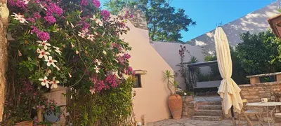 a patio with a table and an umbrella and flowers at Villa ABBA in Plaka