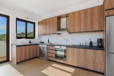 a kitchen with wooden cabinets and stainless steel appliances at Kera Green Villa in Kalyves