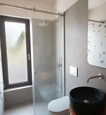 a bathroom with a glass shower and a toilet at Riviera Seafront Balcony in Evthími