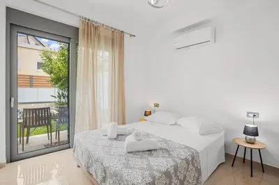 a white bedroom with a bed and a balcony at Park and sea view Villa with Private Pool 2 in Chania Town