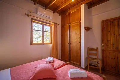 a bedroom with a bed and a window and a chair at BABIS & POPI APARTMENTS in Frangokastello