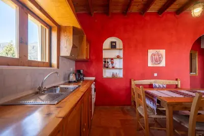 a kitchen with red walls and a table and a sink at BABIS & POPI APARTMENTS in Frangokastello
