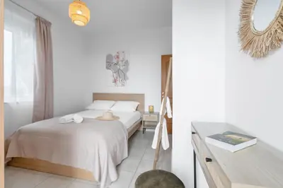 a white bedroom with a bed and a table at Aelia Sea View in Chania Town