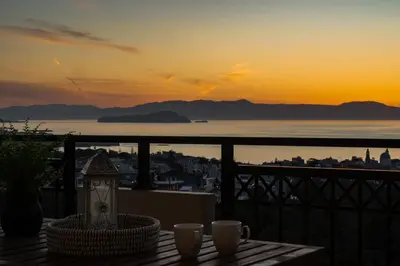 a sunset from a balcony with two cups on a table at Aelia Sea View in Chania Town