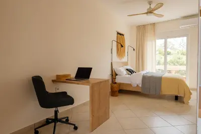 a bedroom with a bed and a desk with a laptop at El Chacha Studio in Galatás