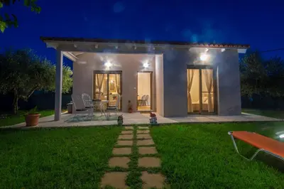 a small white house with a green lawn at night at Coastal Haven Your Oasis by the Sea in Análipsis