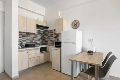 a kitchen with a white refrigerator and a wooden table at Sun Beach Apartment in Chania 3 in Chania Town