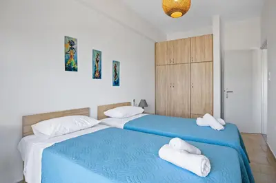 a bedroom with a blue bed with towels on it at Sun Beach Apartment in Chania 3 in Chania Town