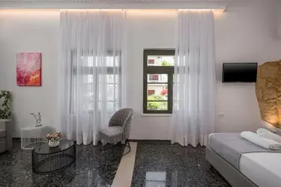 a white room with a bed and a chair and a window at Casa Αrezio in Chania Town
