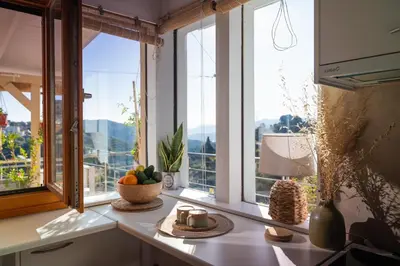 a kitchen with windows and a table with a bowl of fruit at Iris Cretan Mountain Escape in Apothíkai