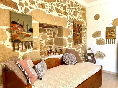 a bedroom with a stone wall with a bed with pillows at Kyparissos Apartment II in Kissamos