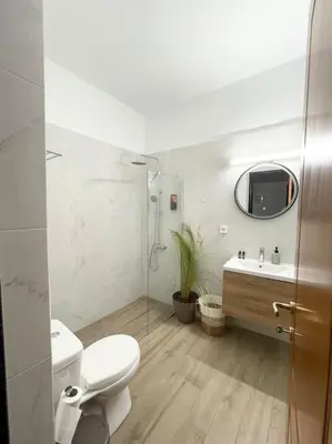 a bathroom with a toilet and a sink and a mirror at Thali central apartment with parking in Chania Town