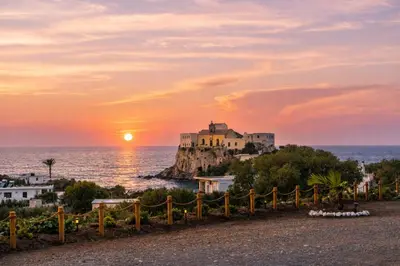 a house on a rock in the ocean at sunset at Holy Sea Smart Suites in Elafonisi