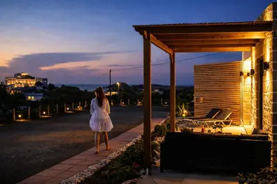 a woman in a white dress walking down a sidewalk at Holy Sea Smart Suites in Elafonisi