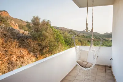 a swinging chair on a balcony with a view at Infinity Wellness Boutique Hotel in Afráta