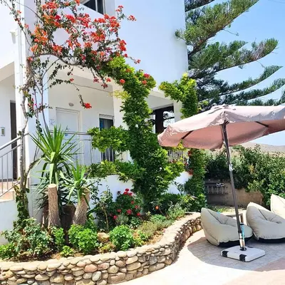 an umbrella sitting in front of a building with flowers at Infinity Wellness Boutique Hotel in Afráta