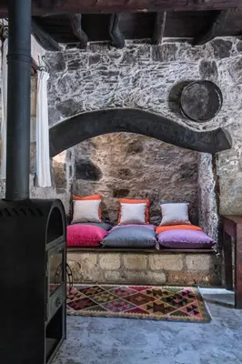 a couch sitting in a stone wall with pillows at Μilia Mountain retreat in Vlátos