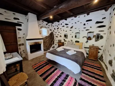 a bedroom with a large bed and a stone wall at Μilia Mountain retreat in Vlátos